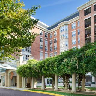 A modern apartment building with lush trees in the foreground on a sunny day.