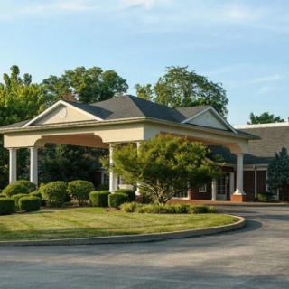 Front entrance of a building with landscaped surroundings and a circular driveway.