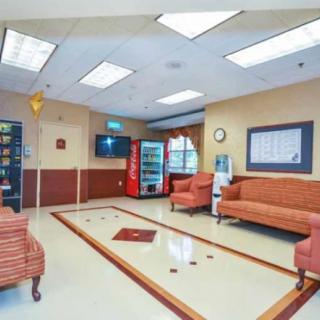 A well-lit waiting room featuring comfortable seating, a soda machine, and a vending machine.