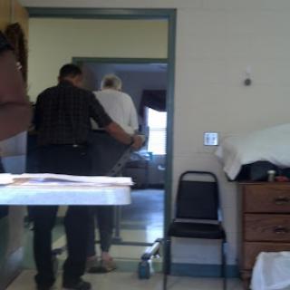 A caregiver assisting an elderly person in navigating a room.