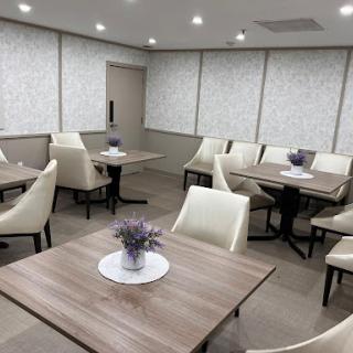 A modern dining area featuring light-colored chairs and wooden tables, designed for community gatherings.