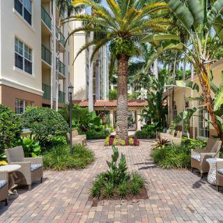A serene courtyard with lush palm trees and comfortable outdoor seating at an apartment complex.