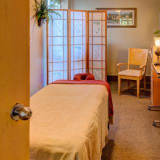 A serene massage room designed for relaxation and wellness, featuring a massage table and calming decor.
