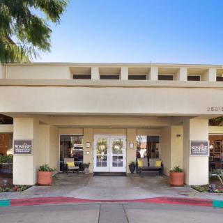 A building entrance with potted plants on either side, captured during the daytime.
