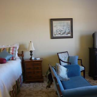 A cozy bedroom with a bed, chair, and television.