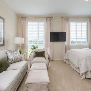 A cozy and modern living area with a sofa, bed, and large windows letting in natural light.