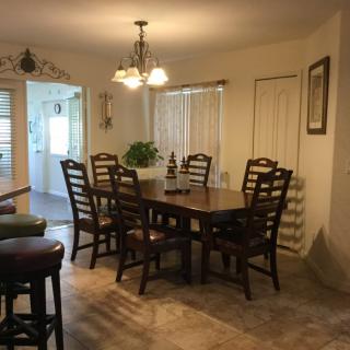 A cozy dining room with a wooden table and chairs, illuminated by a chandelier.
