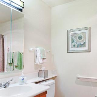 A tidy bathroom with a sink, mirror, and neatly arranged towels.