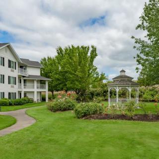 A picturesque garden with a gazebo and a pathway leading to a large house.