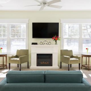 A modern living room with a fireplace and TV, featuring comfortable seating and abundant natural light.