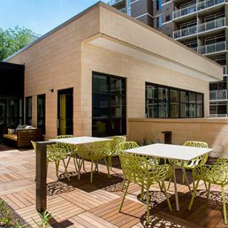 A modern outdoor patio area with tables and chairs, adjacent to a contemporary building.