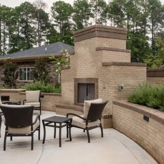 A spacious outdoor patio with a brick fireplace surrounded by comfortable seating.