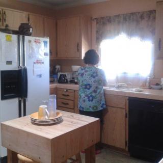 A person standing in a kitchen, facing the sink.