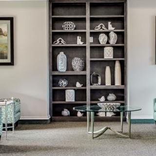 A well-decorated living room featuring shelves with ceramic pieces and modern furniture.