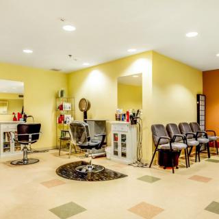 A brightly lit hair salon with styling chairs, mirrors, and a waiting area.