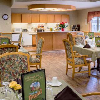 A warmly decorated dining area with tables and chairs, adjacent to a kitchen counter.