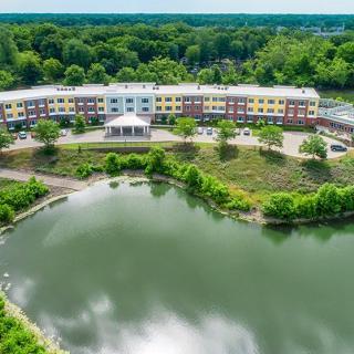 Aerial view of a building surrounded by lush greenery and a tranquil lake.
