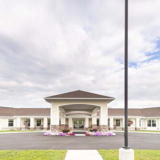 A wide-angle view of a building entrance with a cloudy sky backdrop.