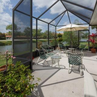 A screened patio with outdoor furniture and a lake view.