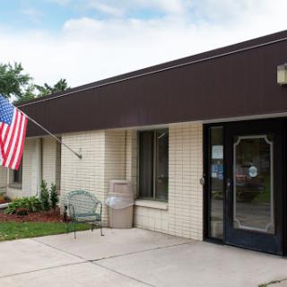 Entrance of a building featuring an American flag and well-maintained landscaping.