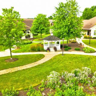A peaceful garden with a gazebo and pathways surrounded by lush greenery.