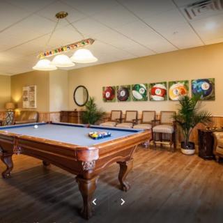 A cozy game room featuring a billiards table with stylish lighting and artistic decor.