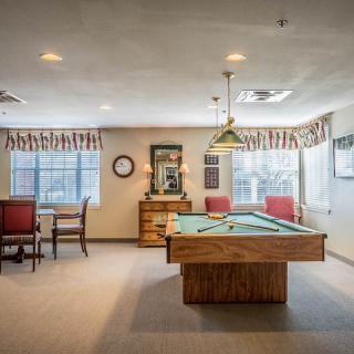 A well-lit game room featuring a billiard table and seating area.