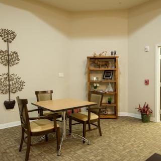 A small, cozy room with a table and chairs, adorned with decor and a bookshelf.