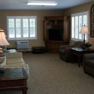 A cozy living room with sofas, a television, and large windows providing natural light.