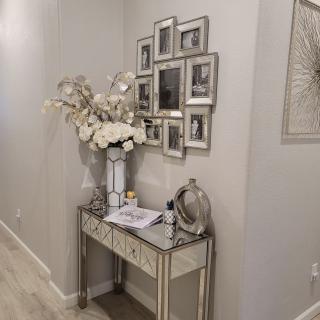 A stylish hallway with a mirrored console table adorned with flowers and framed photos.