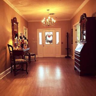 A warmly lit hallway featuring a chandelier, mirror, and classic furniture.