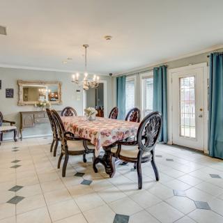 A spacious dining room with a large table, elegant chairs, and a chandelier overhead.