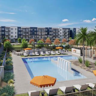 A modern apartment complex featuring an outdoor swimming pool surrounded by sun loungers and palm trees.