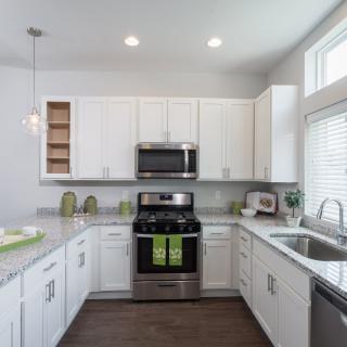 A modern kitchen with white cabinets and stainless steel appliances.