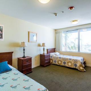 A cozy bedroom with two single beds, featuring lamps and a large window.