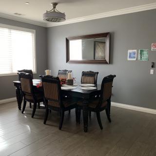 A dining room featuring a dark wooden table with six chairs, a large mirror on the wall, and a chandelier overhead.
