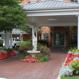 A welcoming entrance with a beautifully landscaped garden and statue under a covered walkway.