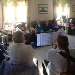 A group of people sitting together in a living room, engaging in a social activity.