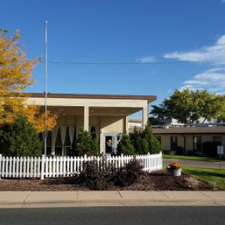 A well-maintained building surrounded by vibrant autumn trees and a white picket fence.