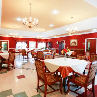 A spacious dining area featuring elegant chandeliers and warm red decor.