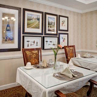 A cozy dining area with elegantly set tables, adorned with framed artwork on the walls.