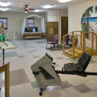 A spacious therapy room equipped with various rehabilitation tools and exercise equipment.