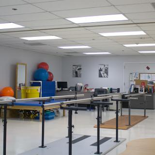 A well-equipped physical therapy room featuring exercise equipment and therapy bars.