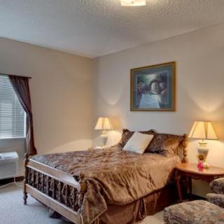 A cozy bedroom with a neatly made bed, lamps on nightstands, and a large window with curtains.