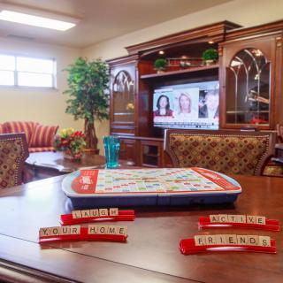 A cozy living room setup with a Scrabble game ready to play on the table, while the television is on in the background.