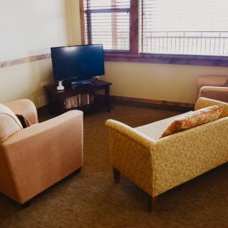 A cozy living room with a sofa, armchair, and a television.