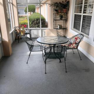 A cozy screened patio with a metal table and chairs, adorned with plants.