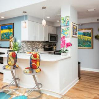 A modern kitchen with colorful bar stools and vibrant artwork.