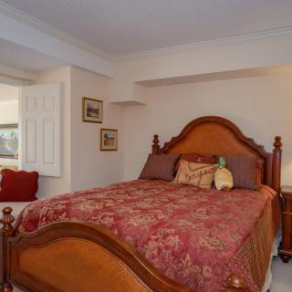 A cozy bedroom with a wooden bed frame and a red patterned comforter.