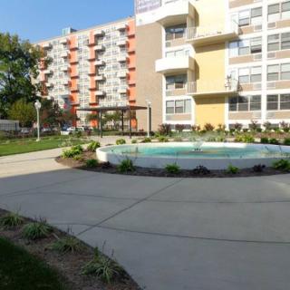 A modern apartment building with landscaped surroundings and a paved walkway.